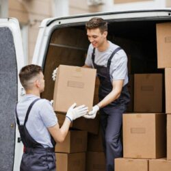 two-young-handsome-movers-wearing-uniforms-are-unloading-the-van-full-of-boxes-house-move-mover