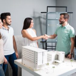 business-partners-shaking-hands-with-engineer-by-architectural-model-meeting